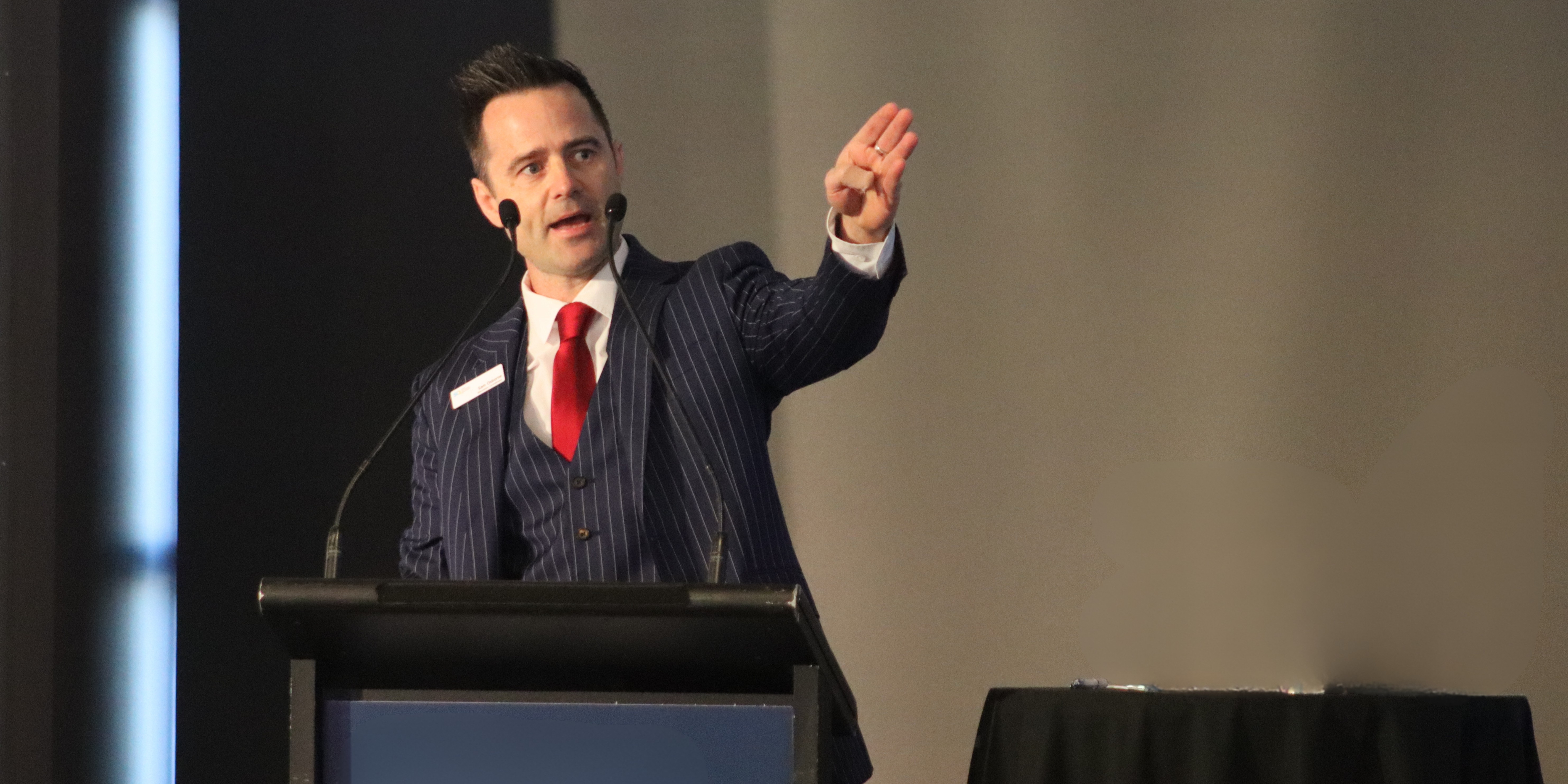 Sam Osborne speaking on stage about conflict transformation through the Demartini Method