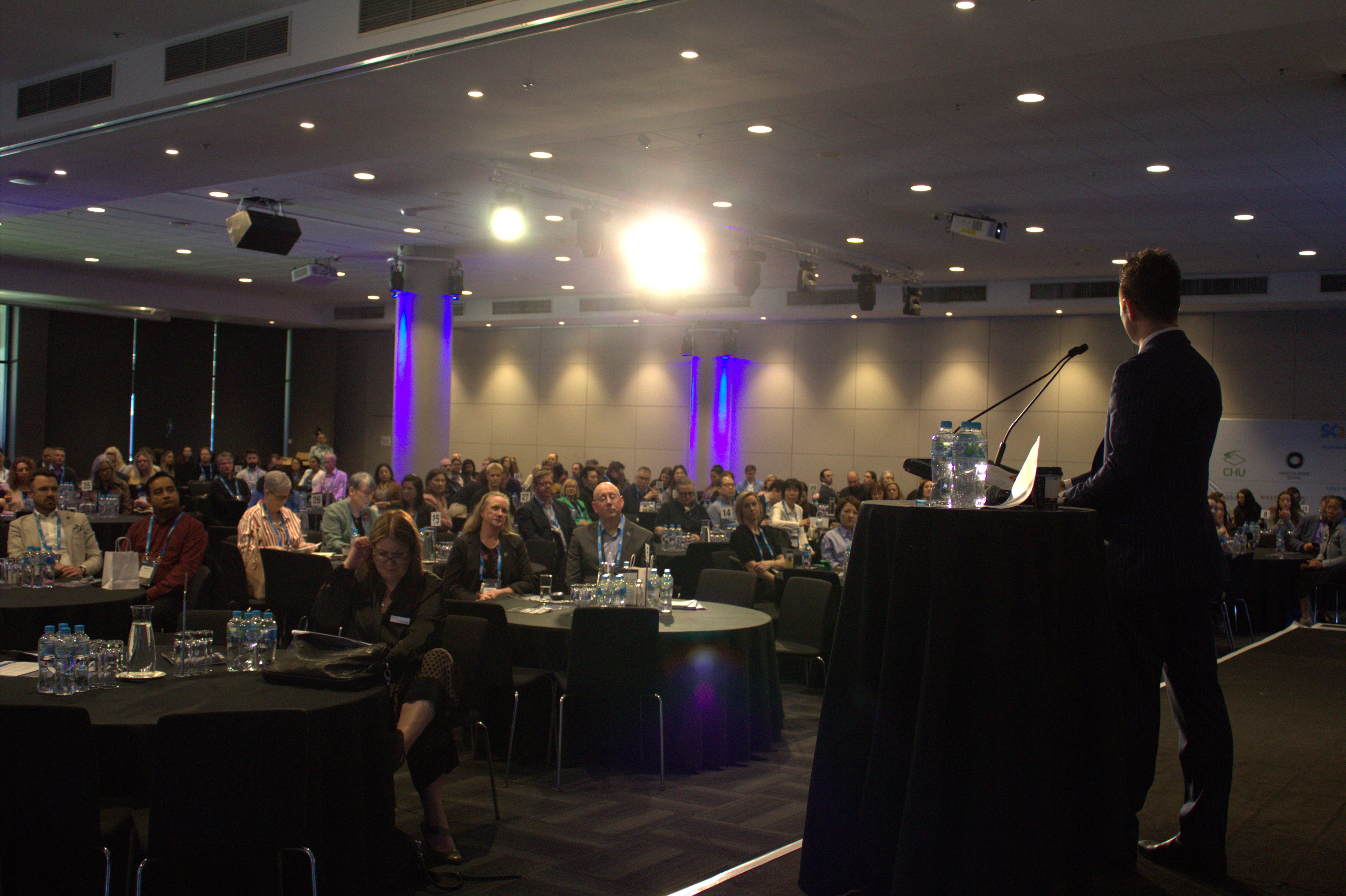 Sam Osborne speaking on stage delivering Demartini Method keynote